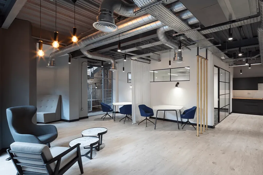 Breakout space with exposed services, pendant lights and brass screen at the University of Law Bristol