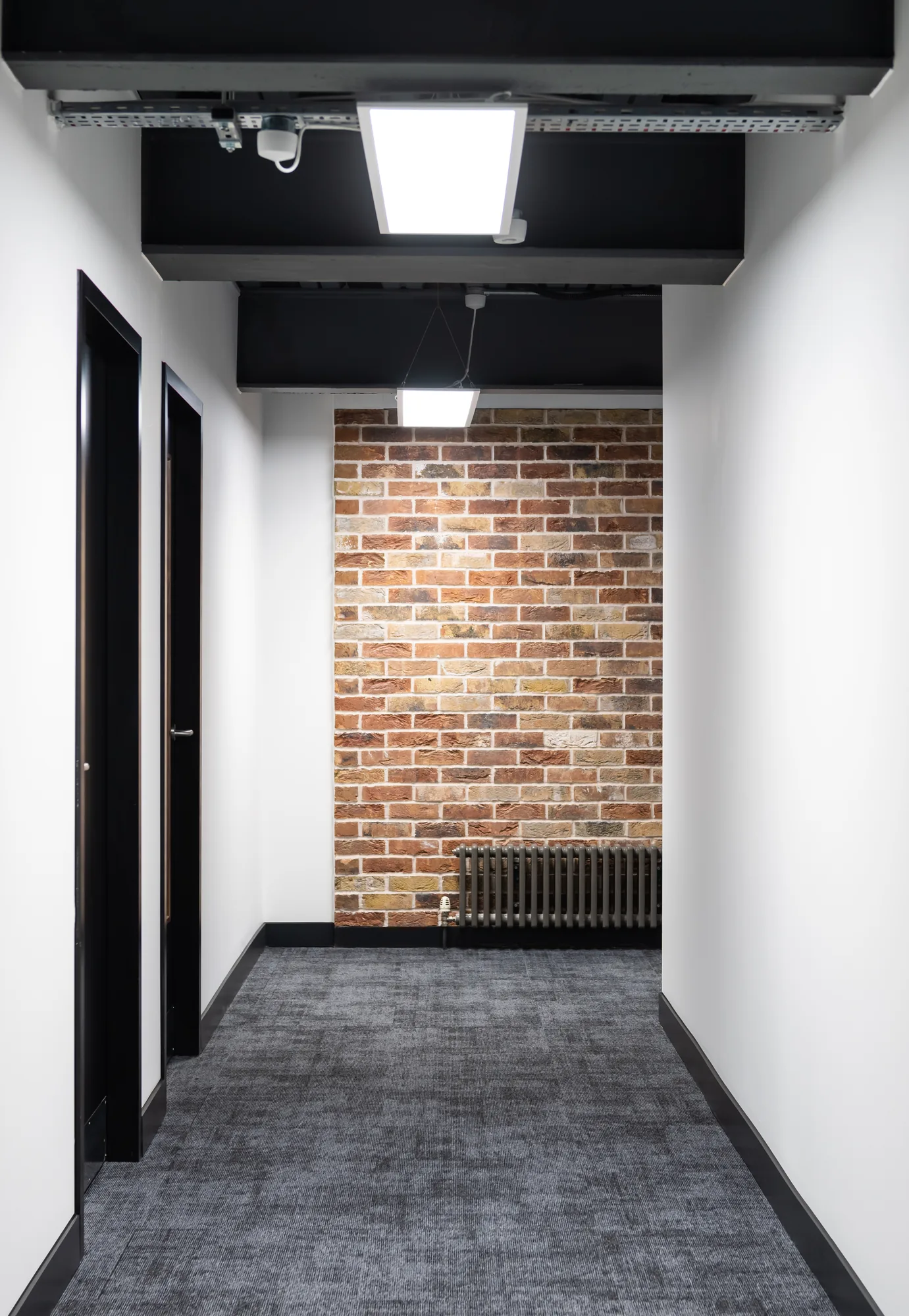 Exposed brick wall at the end of an Arden University corridor
