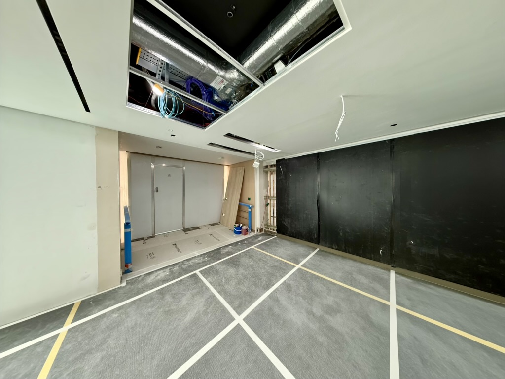 A treatment room mid-installation — ductwork routed above while wall panels go in.